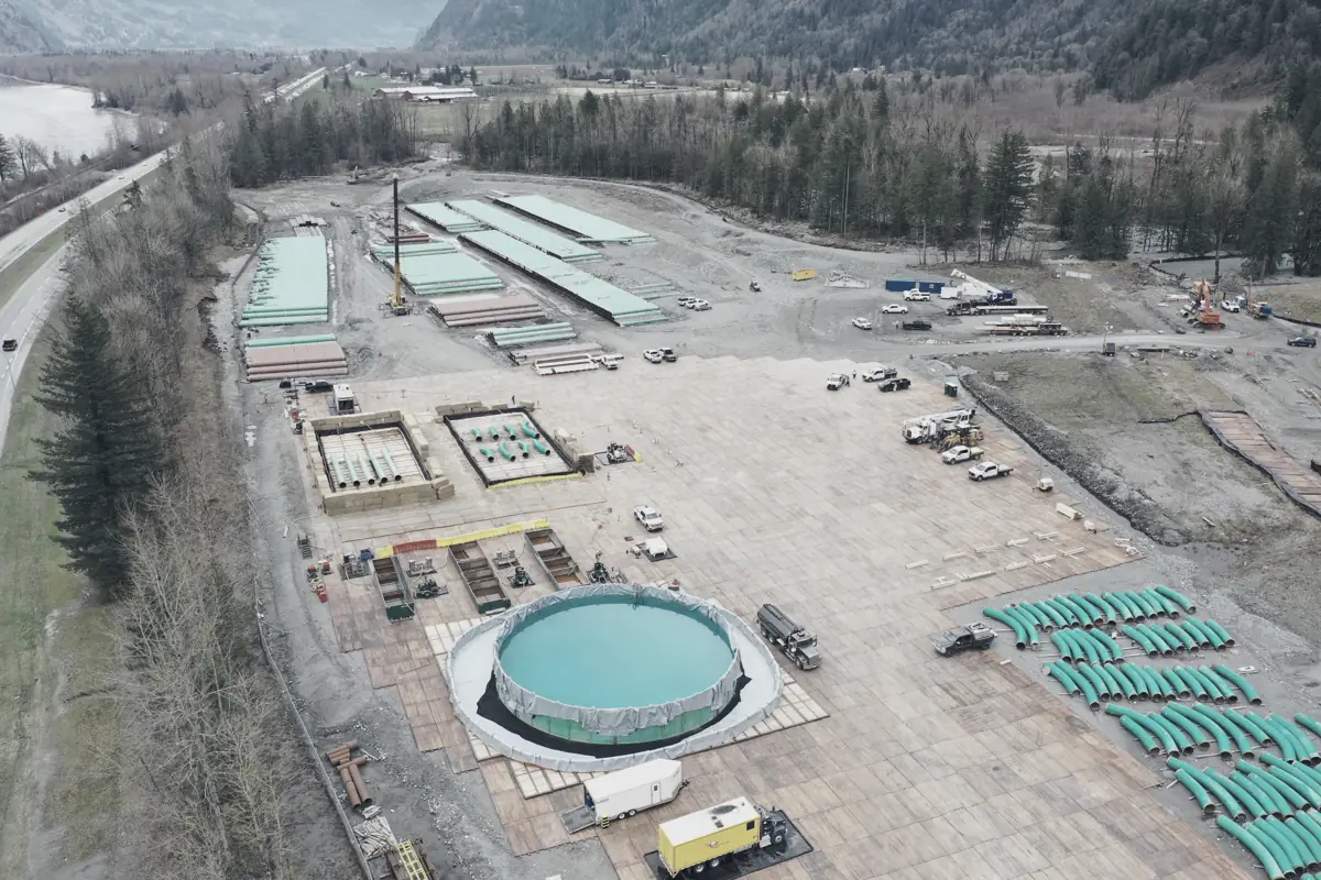 Aerial view of a construction site with a tank foundation, laydown yards and stockpiled pipe