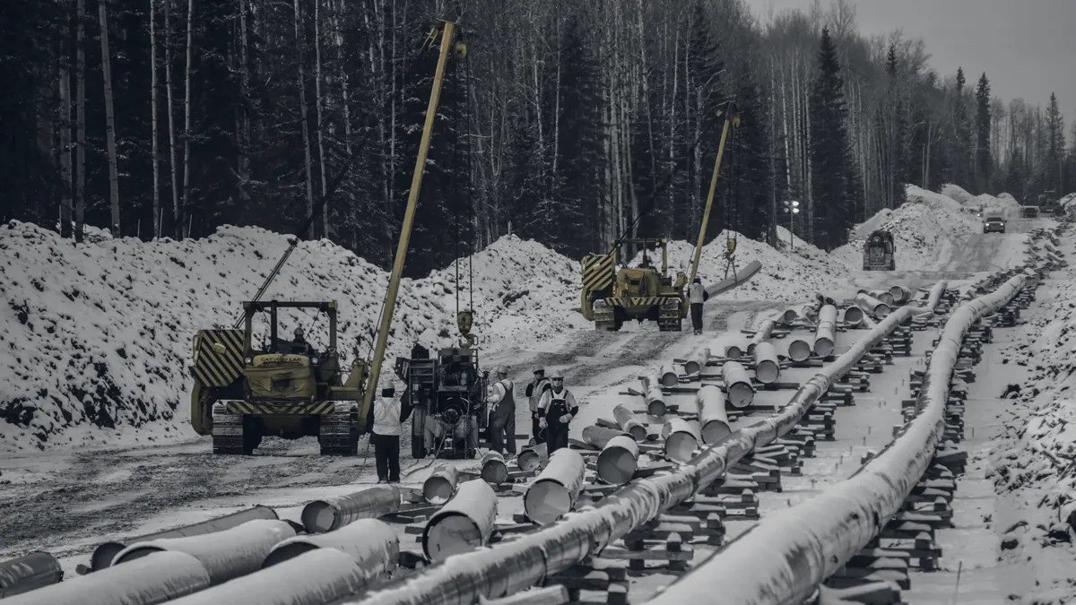 Pipe joints strung out along a snowy right-of-way