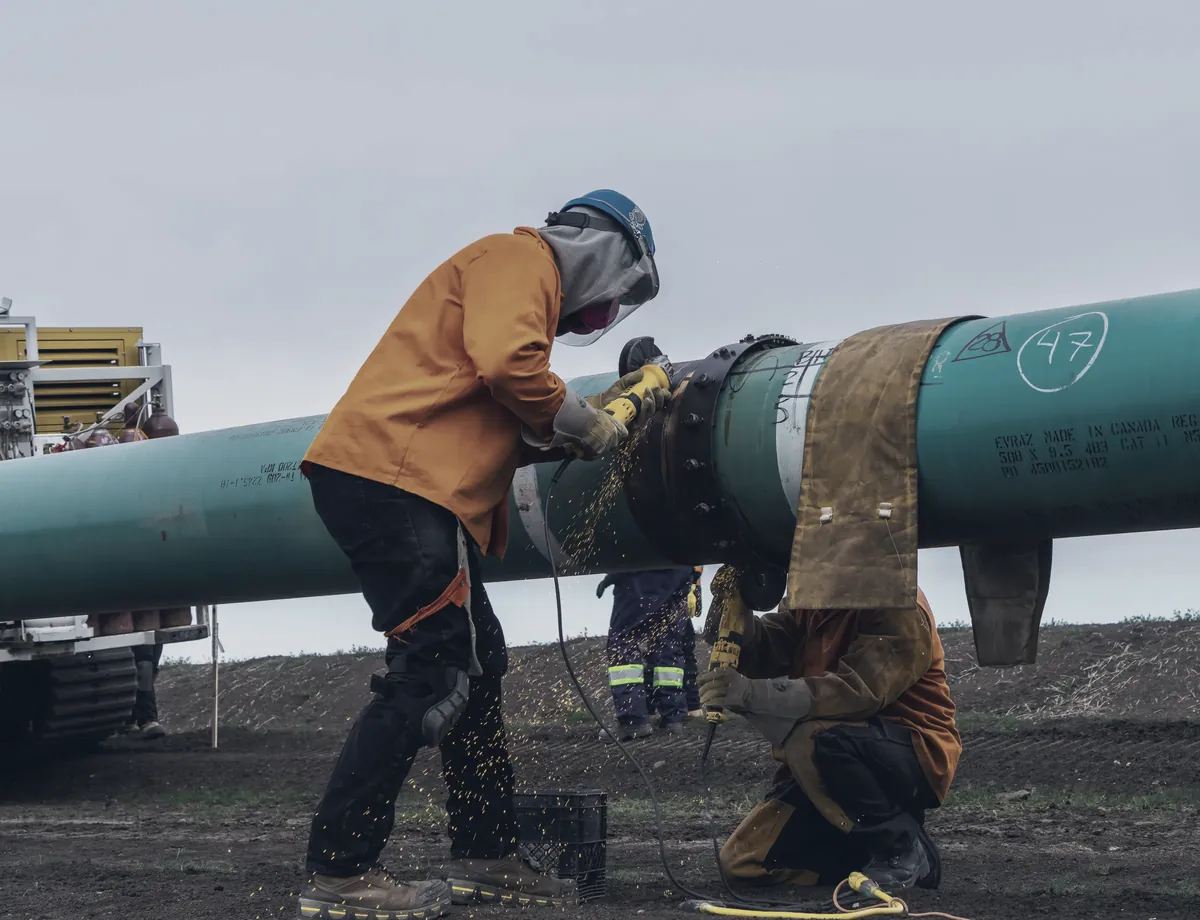 A welder at a girth weld on green coated pipe